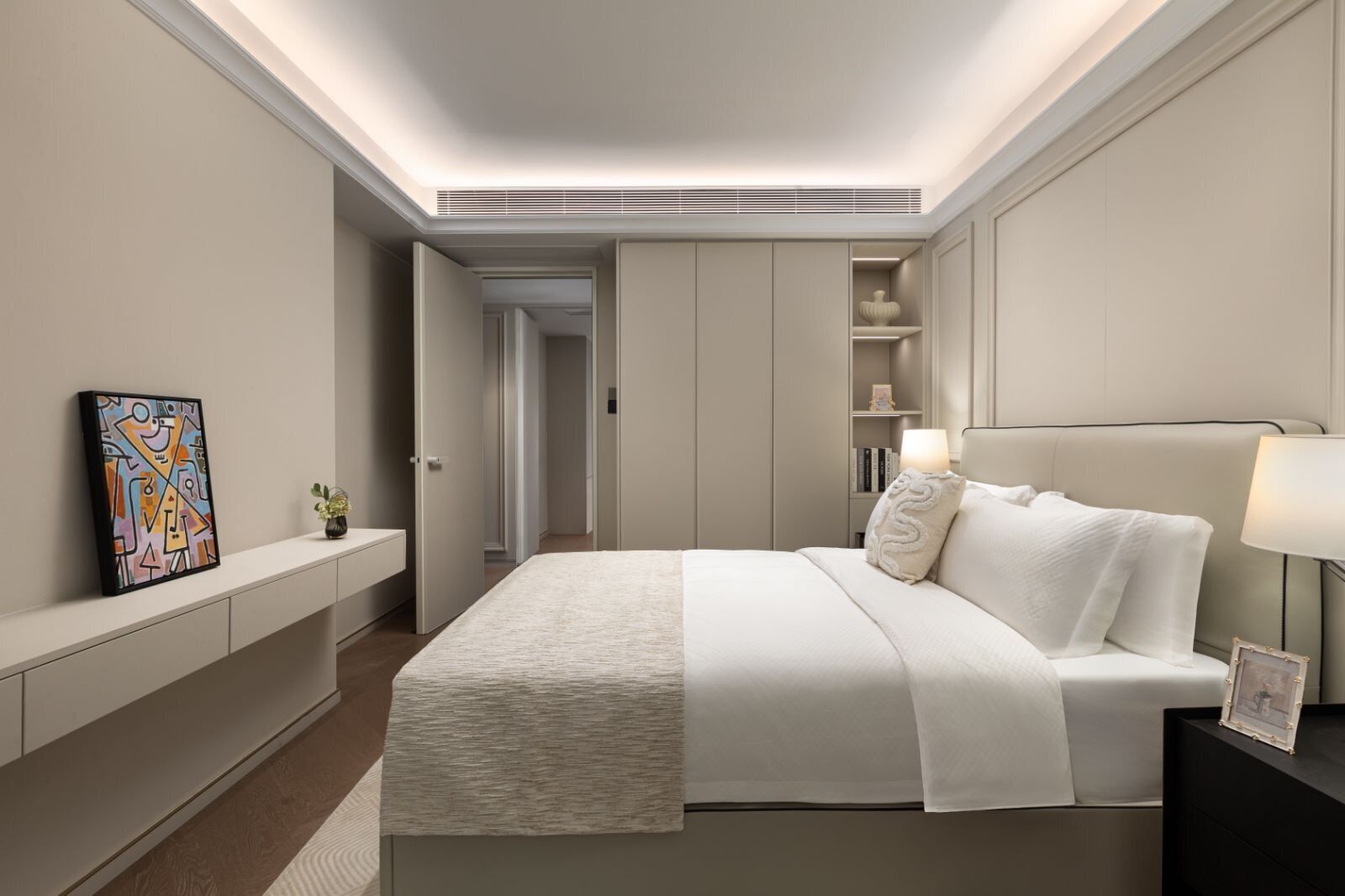 Une chambre à coucher moderne avec un lit, une table de chevet, une lampe et un tableau au mur.
