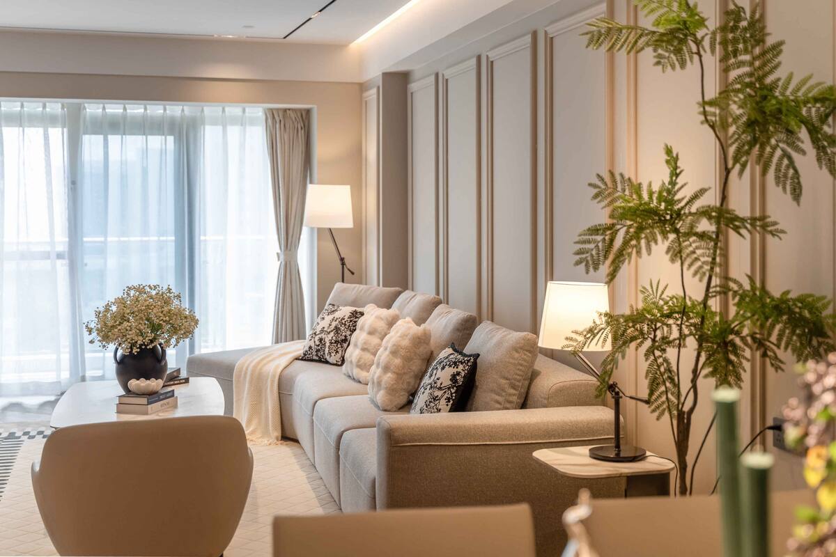 Ein modernes Hotelzimmer mit einer Couch, einem Couchtisch, einer Lampe und einem Blumentopf.