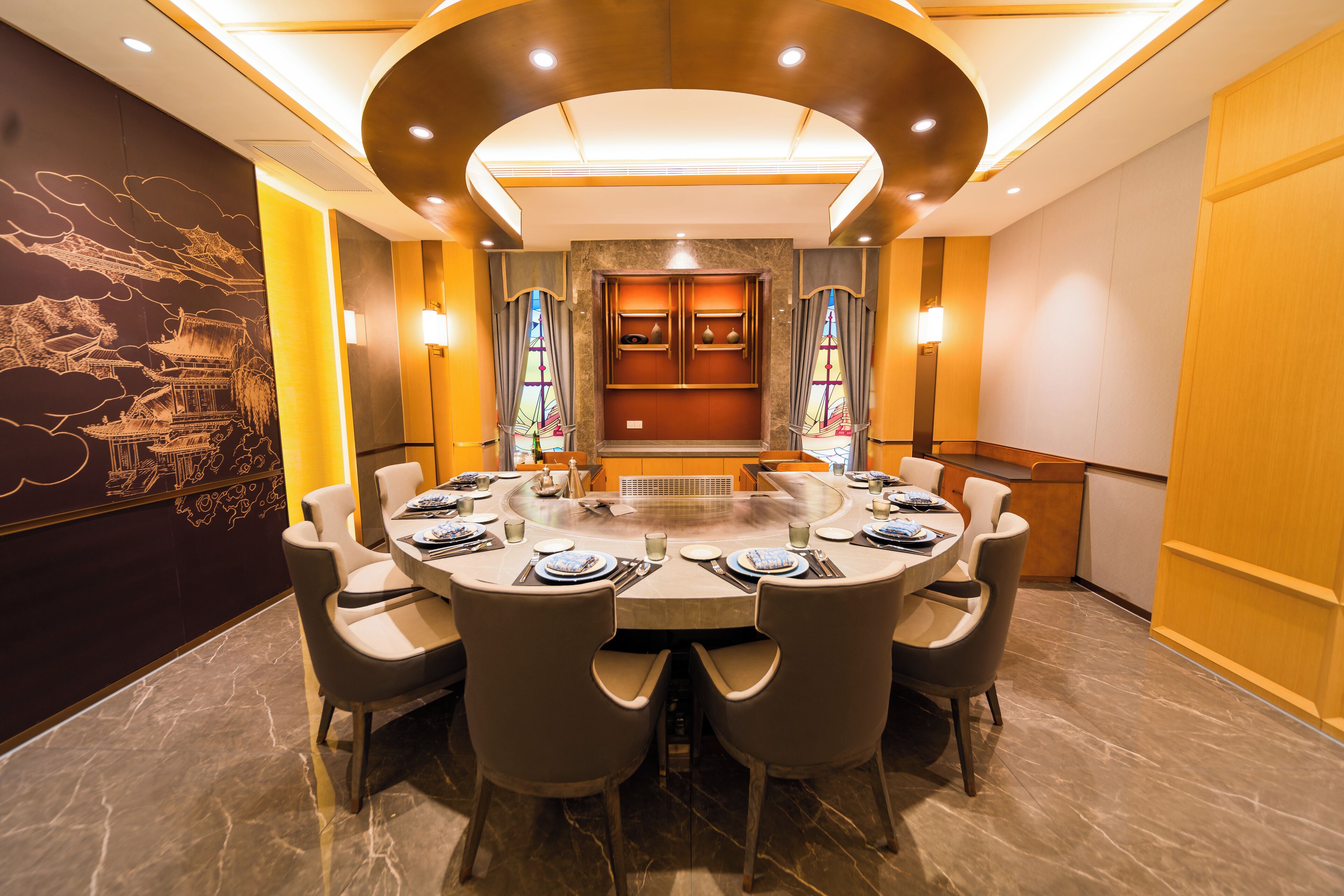 A conference room with a round table, six chairs, and a central fireplace.