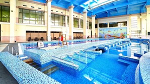 Una piscina interior con varias pistas de natación, un trampolín y un mural de vida marina en la pared.
