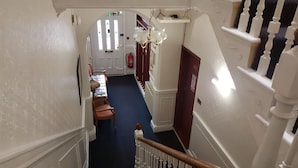 A narrow hallway with a blue carpet, white walls, and a white door with stained glass windows.
