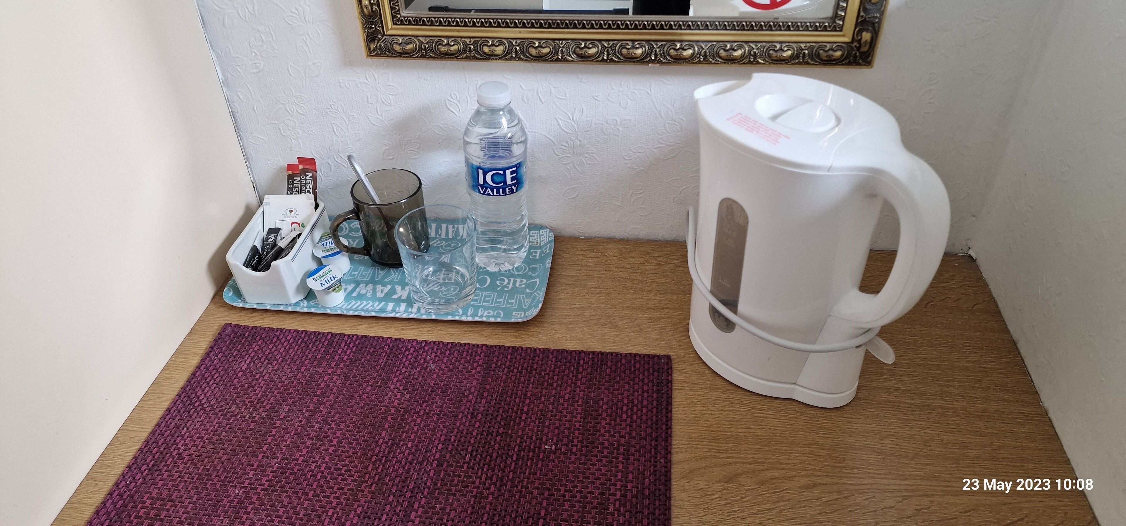 Una mesa pequeña con una botella de agua, una taza, un termo y una bandeja con varios objetos.
