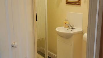 Baño con ducha, lavamanos, inodoro y espejo.