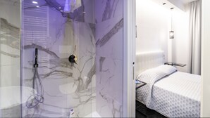 A modern bathroom with a marble shower wall, a handheld showerhead, and a glass-enclosed shower. - Chez Anna B&B (Naples)