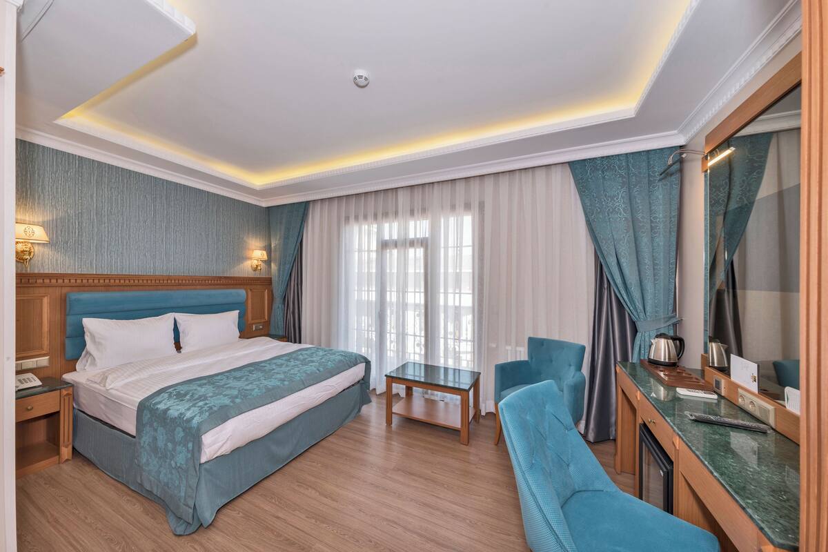 Habitación de hotel con cama, escritorio, silla, mesita y espejo.