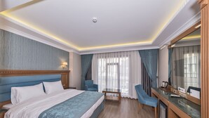A hotel room with a large bed, a desk, a chair, and a television. - Magnaura House Hotel (Istanbul)