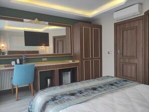 A hotel room with a bed, a desk with a chair, a large mirror, and a wardrobe. - Magnaura House Hotel (Istanbul)