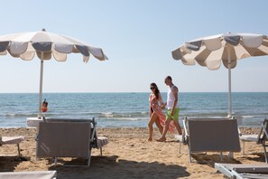 Privat strand, hvit sand, solsenger og parasoller