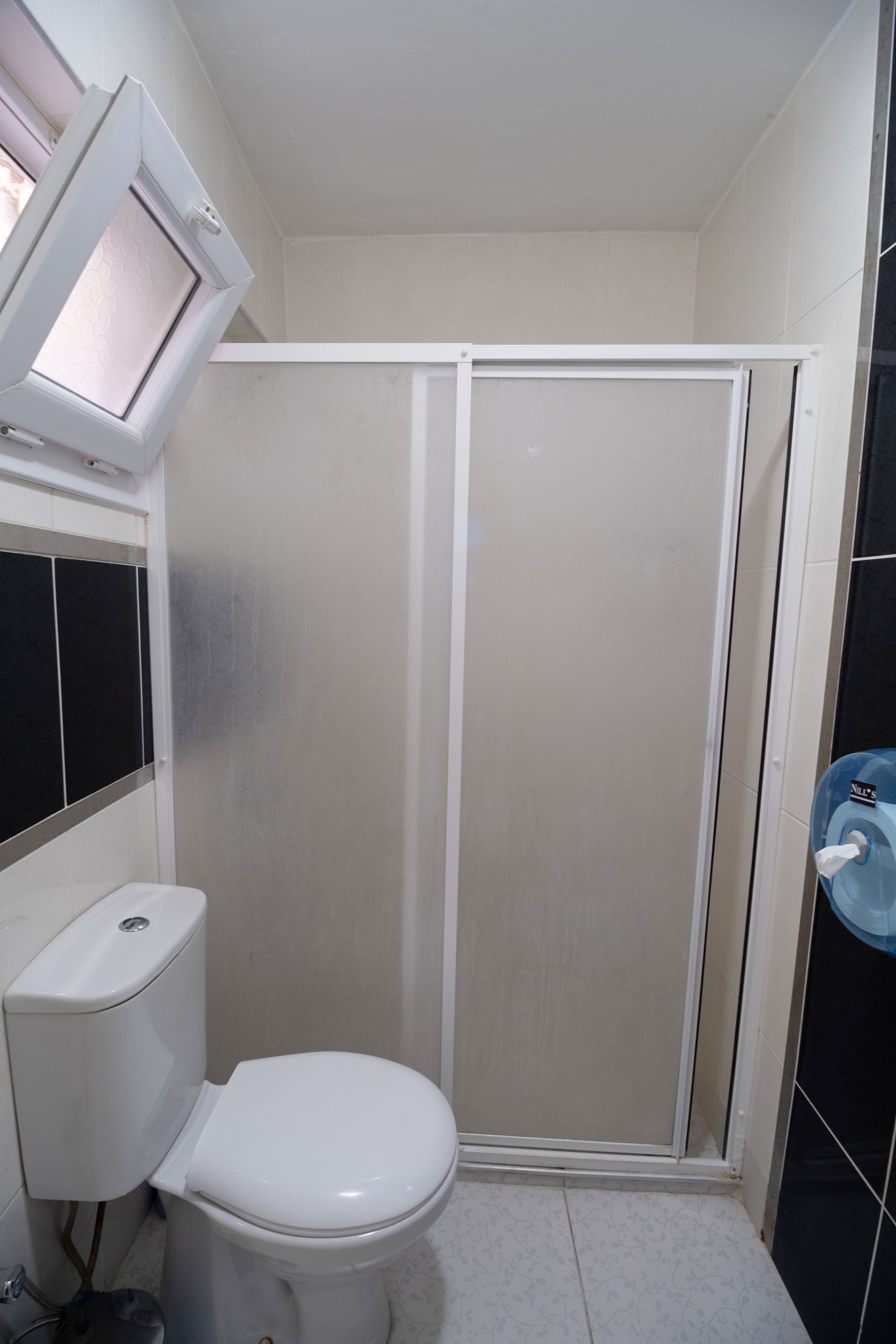 Un baño pequeño con inodoro, cabina de ducha y secador de manos.