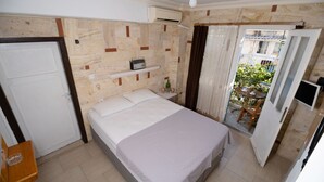A bedroom with a bed, a shelf with a radio, an air conditioning unit, and a view of the outside balcony. - Foca Ensar Hotel (Foça)