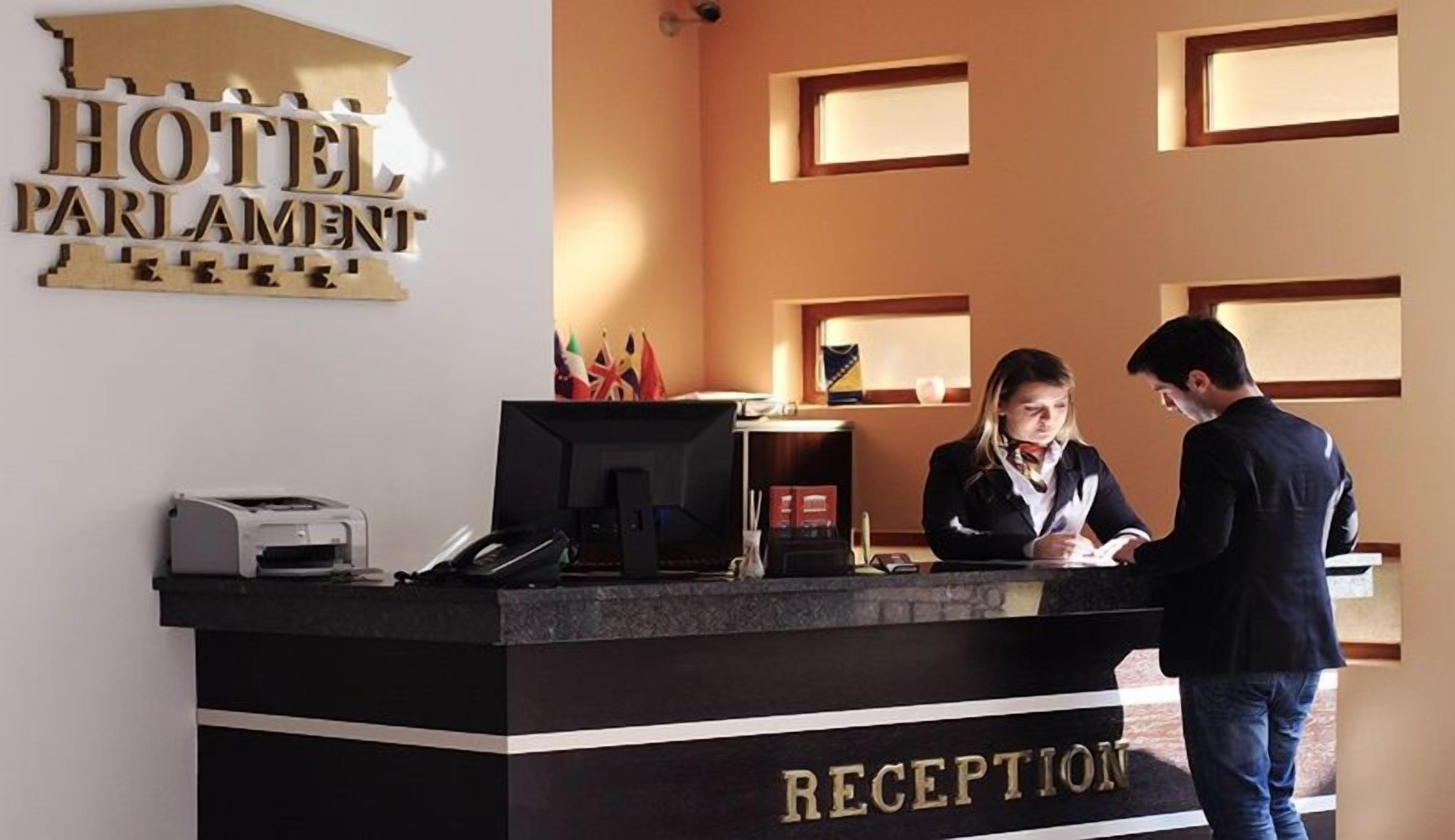 En hotellreception med en skylt som visar texten: ”HOTEL PARLAMENT – RECEPTION”.