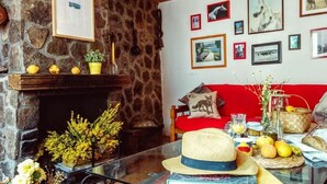 A cozy living room with a stone fireplace, a red sofa, and various decorative items including books, a hat, and a basket. - El Refugio de Gredos - Hostel (Navarredonda de Gredos)