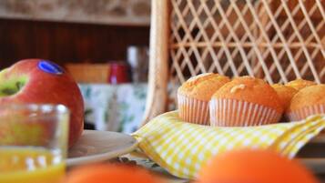 A wicker chair with a plate of muffins and a glass of orange juice.