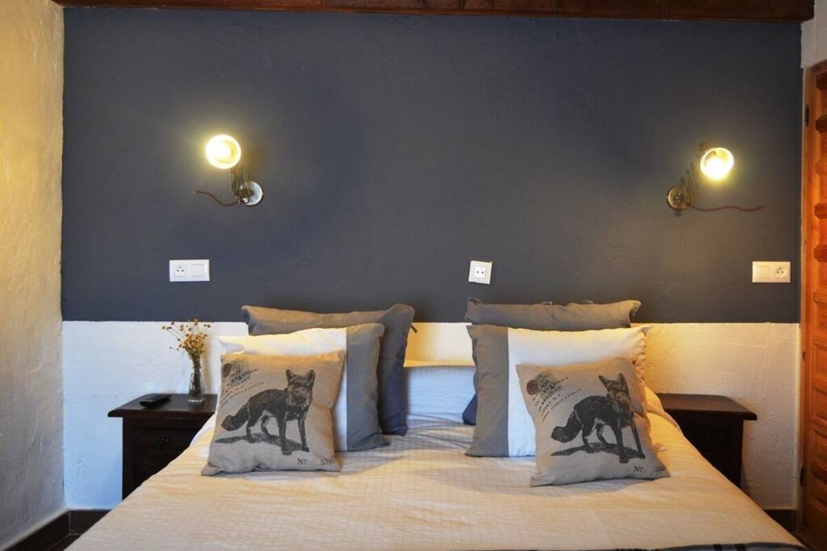 Een slaapkamer met een bed, twee nachtkastjes en twee wandlampen.