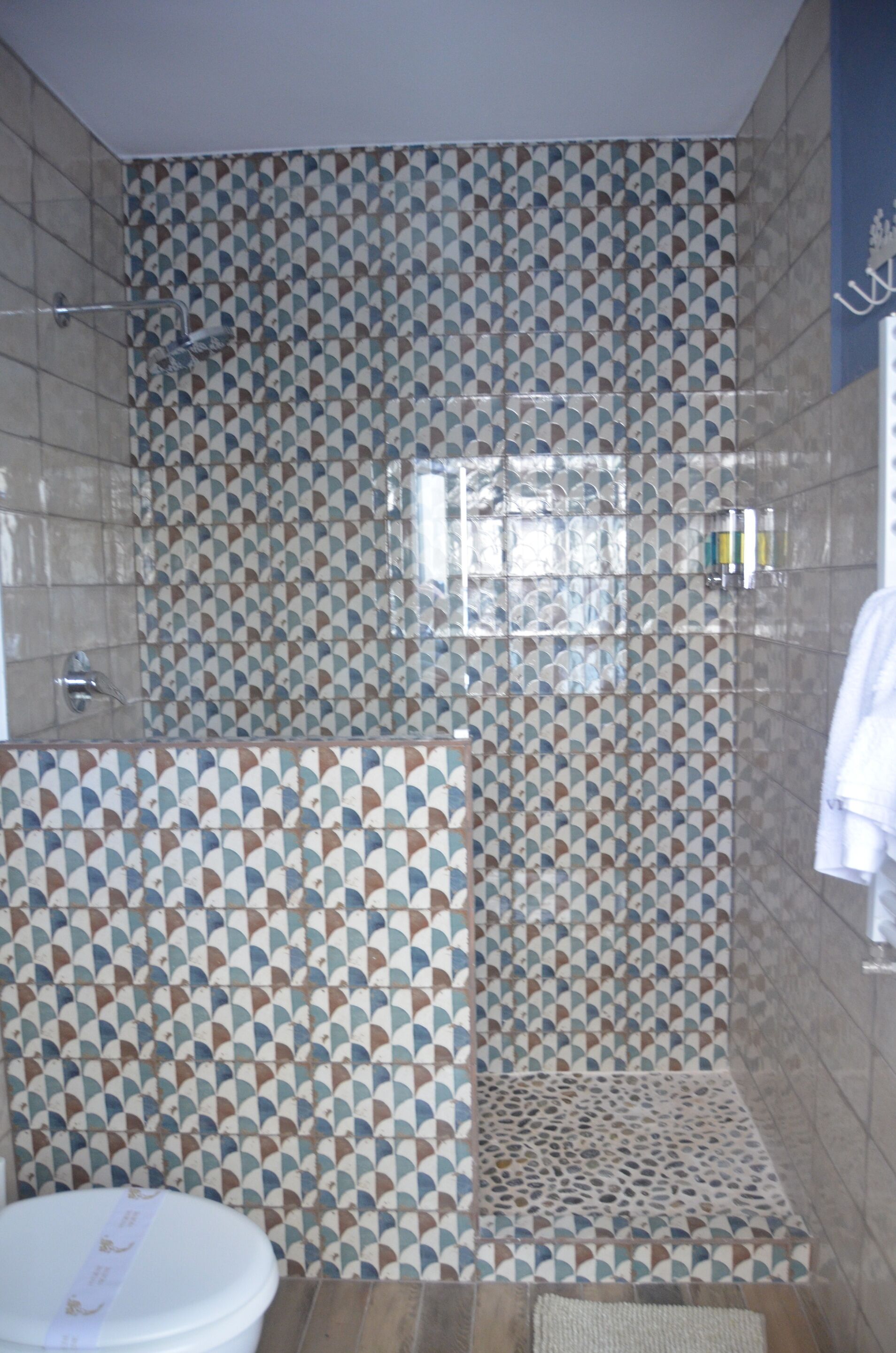 A bathroom with patterned tiles, a toilet, and a shower area.