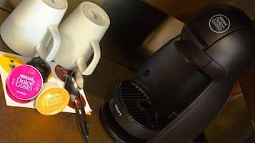 Eine Kaffeemaschine, zwei weiße Tassen und ein Schlüsselsatz auf einer Holztischplatte.
