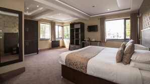 A spacious bedroom with a large bed, a desk, and a wardrobe. - Grainger Apartments (Newcastle-upon-Tyne)