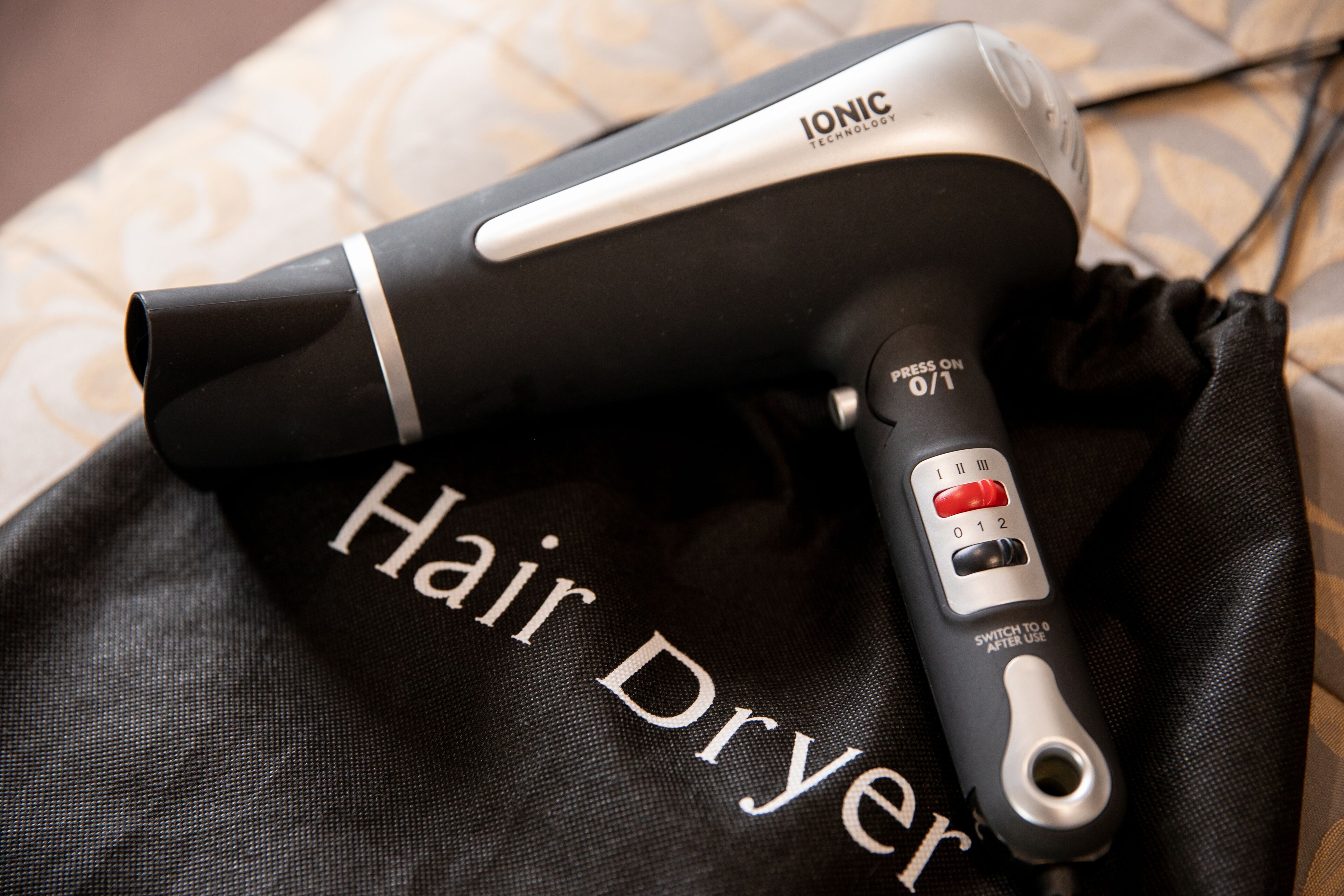Un secador de pelo con un panel de control y una bolsa negra con la inscripción 'Hair Dryer'.