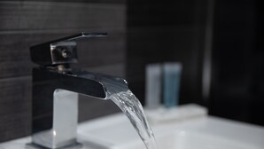 A modern bathroom with a chrome faucet and clear water flowing into a white sink. - Grainger Apartments (Newcastle-upon-Tyne)