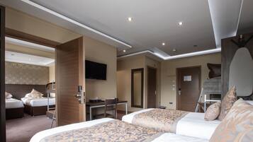 Una habitación de hotel con dos camas, un escritorio, una silla, un televisor y un espejo.