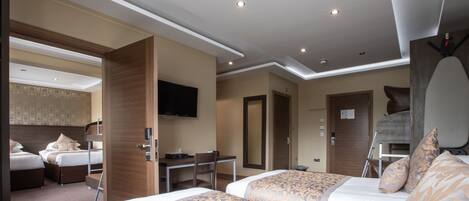 A hotel room with two beds, a desk, a chair, a television, and a mirror.