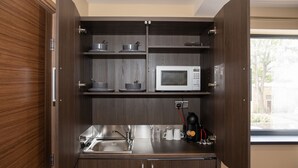 A compact kitchen with a microwave, coffee maker, and a sink. - Grainger Apartments (Newcastle-upon-Tyne)