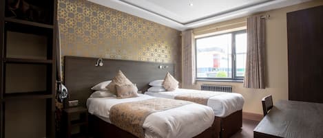 Ett hotellrum med två sängar, ett skrivbord och en garderob.
