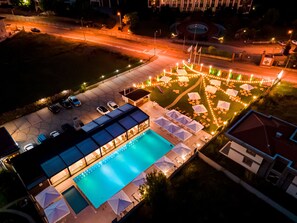 Vista aérea de un hotel con piscina, zona de estar al aire libre y aparcamiento.