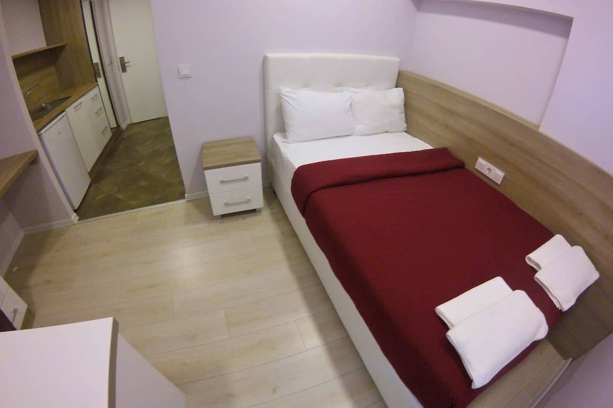 A small, neatly arranged bedroom with a bed, a nightstand, and a wooden cabinet.
