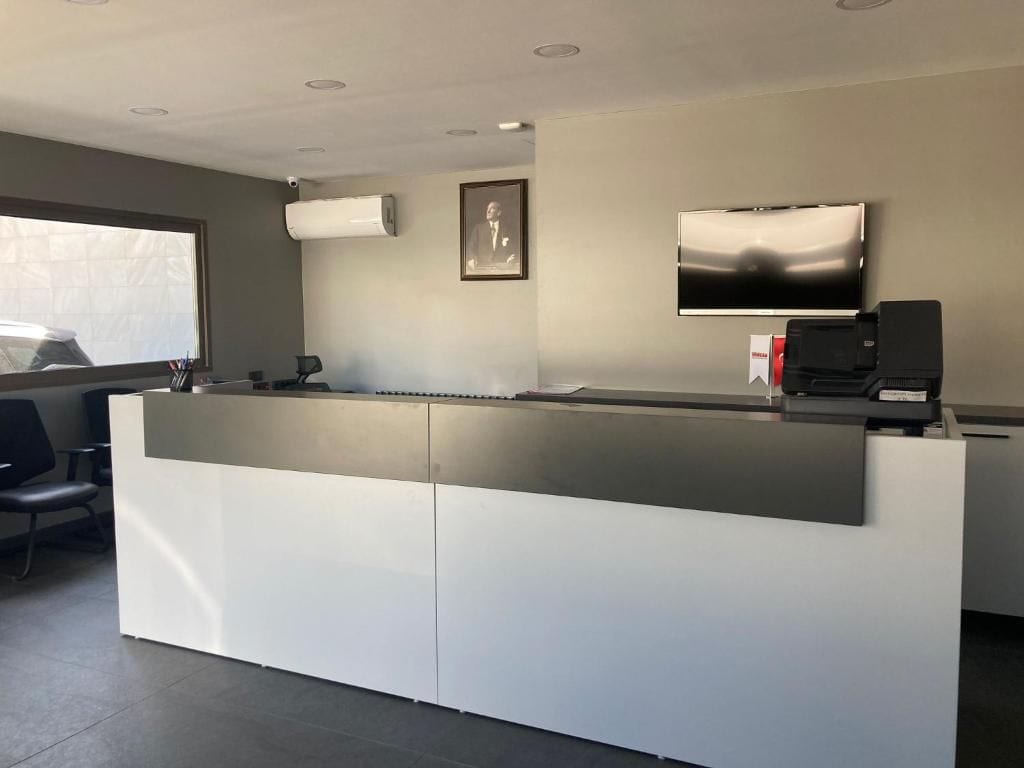 Un mostrador de recepción con un televisor de pantalla plana, un cuadro enmarcado y un altavoz en la pared.