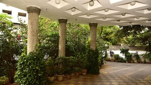 Un espacio al aire libre techado con piso a cuadros, columnas y plantas en macetas.