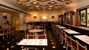 Un restaurante con varias mesas y sillas, un piso estampado y un techo con vidrieras.