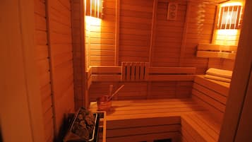 A sauna with wooden benches, a radiator, and a tray of rocks.