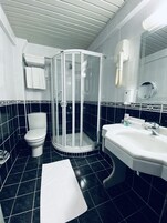 A modern bathroom with a glass shower enclosure, a toilet, and a sink with toiletries.
