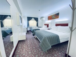 A hotel room with two beds, a desk, and a chair. There is a window with curtains, a painting on the wall, and a patterned carpet. - Bugday Hotel (Ankara)