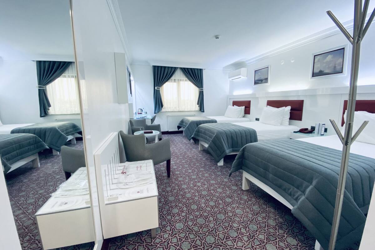 A hotel room with two beds, a desk, a chair, and a mirror.