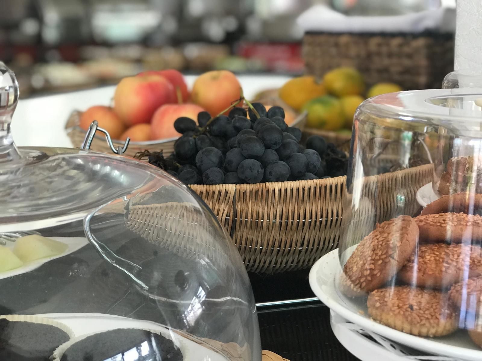 Buffet com diversos alimentos, incluindo maçãs, mirtilos e doces.