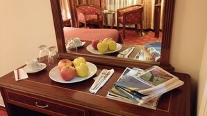 Un aparador de madera con un espejo, un plato de manzanas, una taza y periódicos.