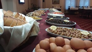 Una mesa de buffet con distintos alimentos, como pan, aceitunas y huevos.