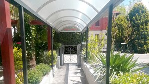 A covered walkway leading to a building entrance with a metal gate. - Hotel Rita (Cervia)