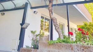 A multi-story building with a balcony, a palm tree, and red flowers. - Hotel Rita (Cervia)