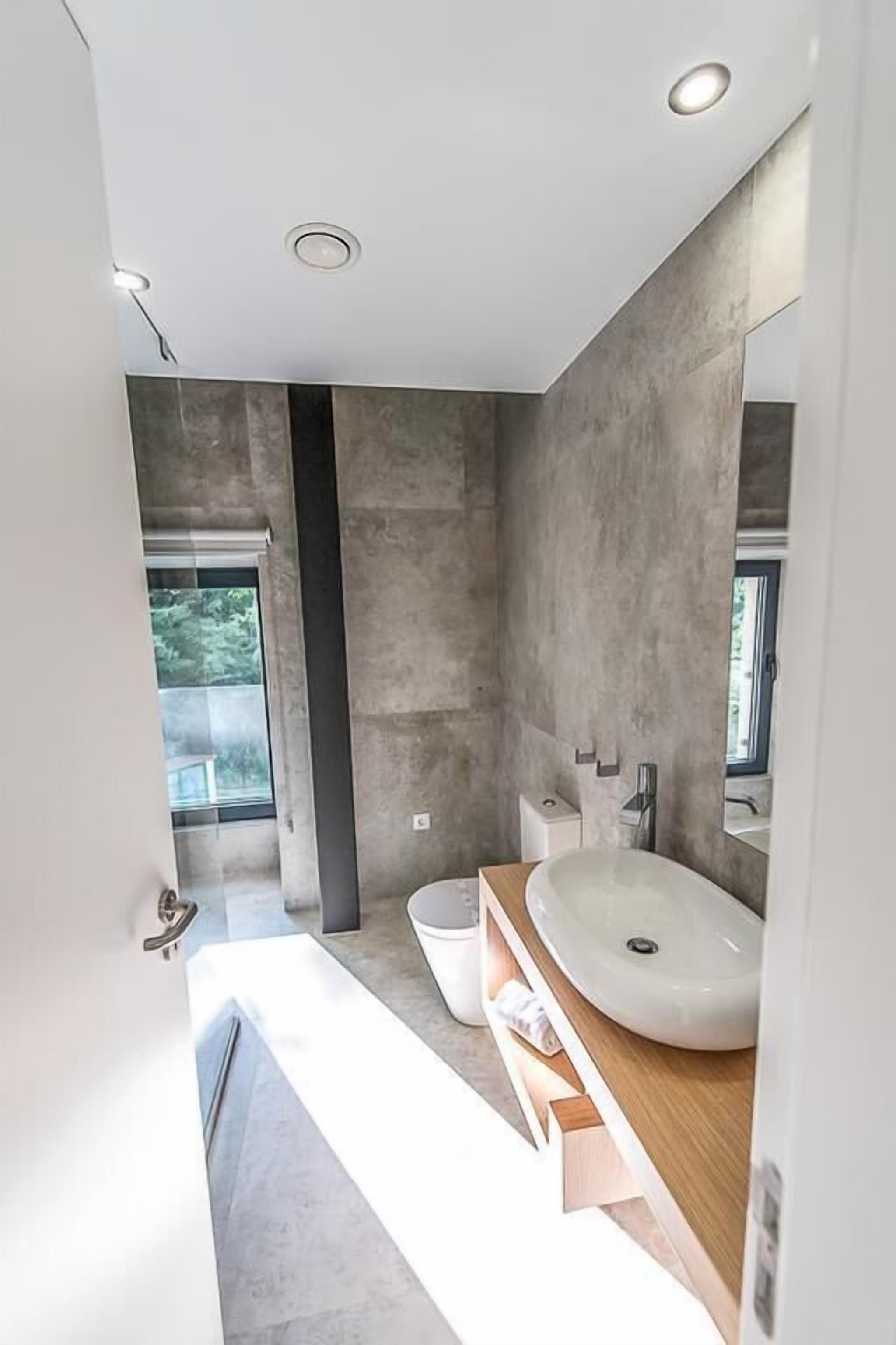 Un baño moderno con un lavamanos grande, un espejo y una ventana que deja entrar luz natural.