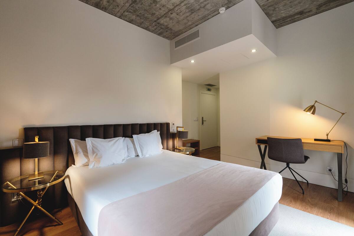 Ein modernes Hotelzimmer mit einem großen Bett, einem Schreibtisch und einem Stuhl.