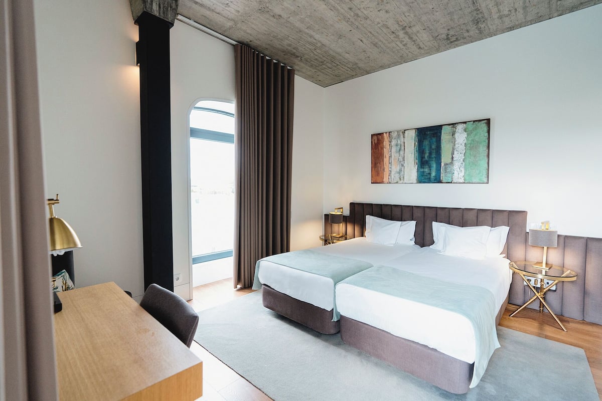 Ein Hotelzimmer mit einem großen Bett, einem Schreibtisch, einem Sessel, einer Lampe und einem Bild an der Wand.