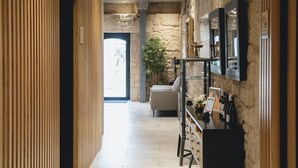 Een gang met houten lambrisering, een stenen muur, een aan de muur bevestigde televisie en een plant.
