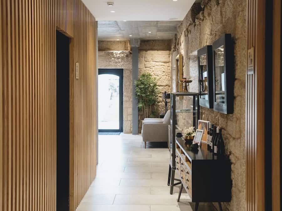 Un pasillo con paneles de madera, una pared de piedra, un televisor montado en la pared y una planta.