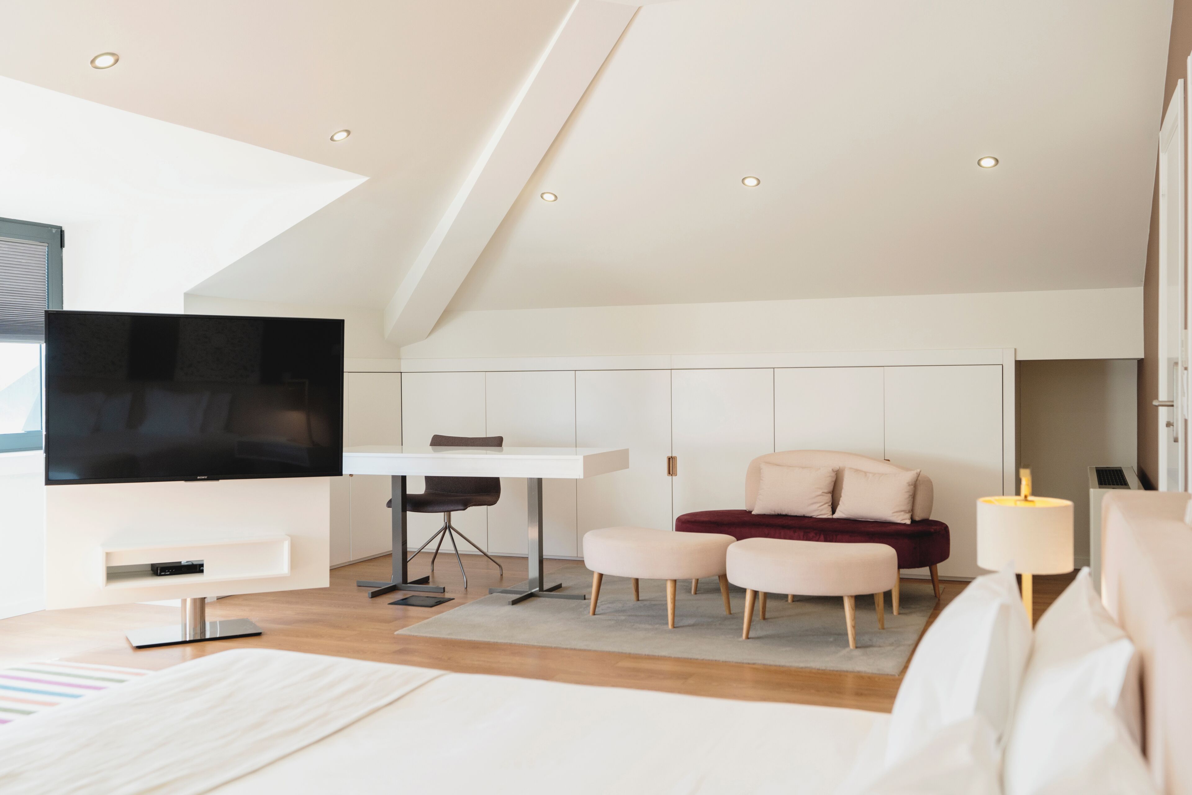 Un dormitorio moderno con televisor, escritorio y zona de estar.