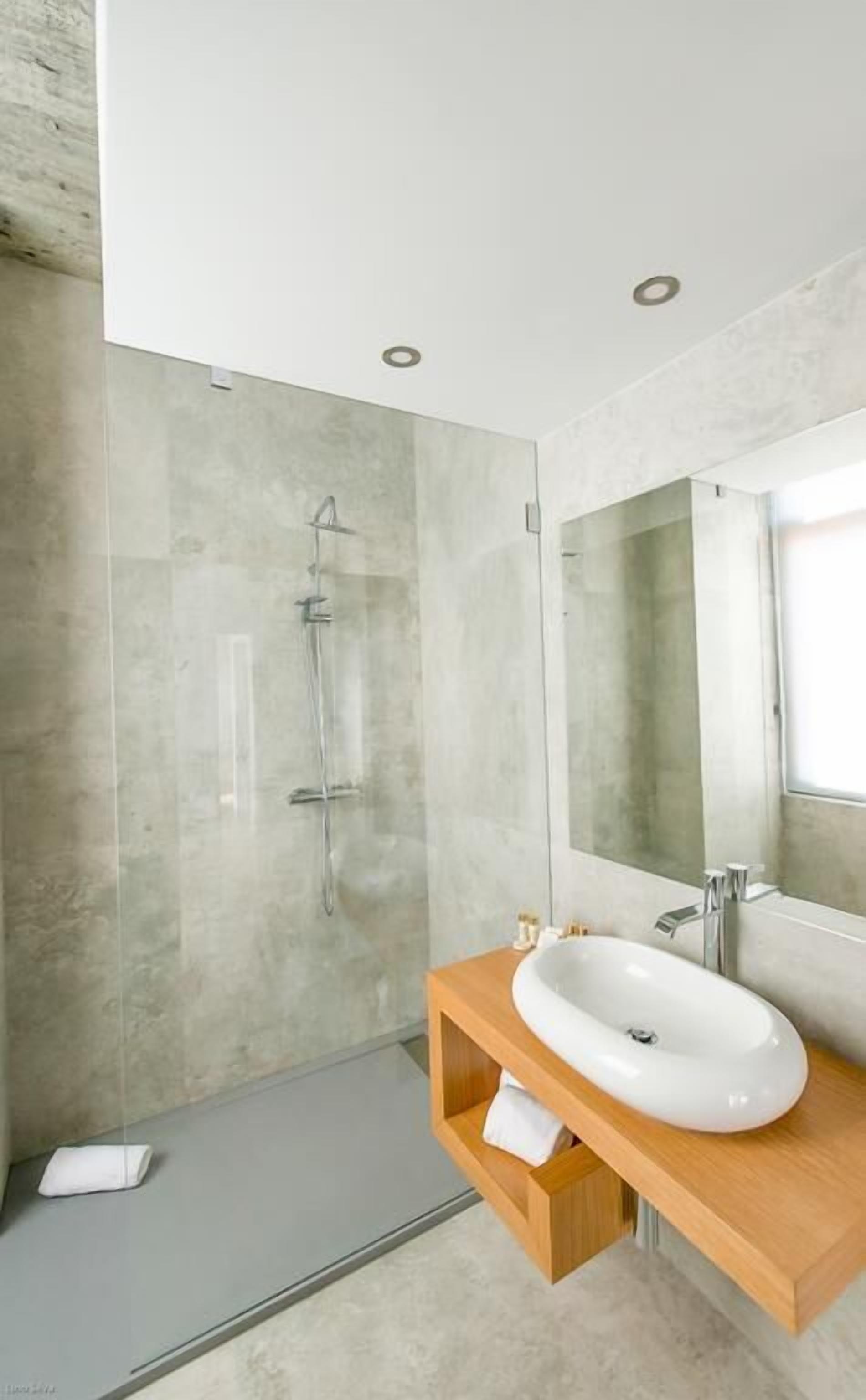 Een moderne badkamer met een grote spiegel, een houten wastafelmeubel en een douchecabine met glazen wanden.