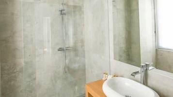 Een moderne badkamer met een grote spiegel, een houten wastafelmeubel en een douchecabine met glazen wanden.