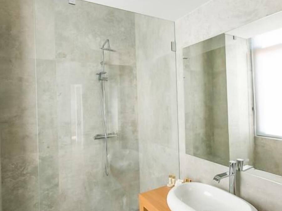 Een moderne badkamer met een grote spiegel, een houten wastafelmeubel en een douchecabine met glazen wanden.